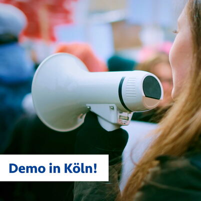 Eine Frau hält ein Megaphon in der Hand, man sieht sie nur seitlich.