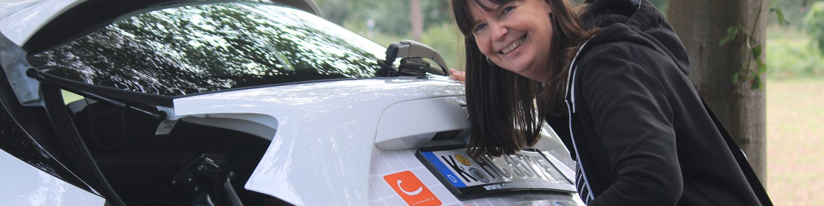 Frau schließt den Kofferraum eines Car-Sharing-Fahrzeugs