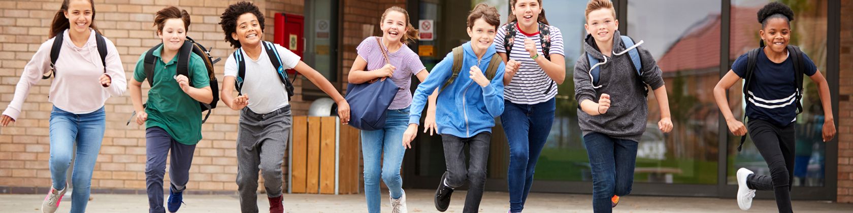 Kinder laufen lachend aus der Schule