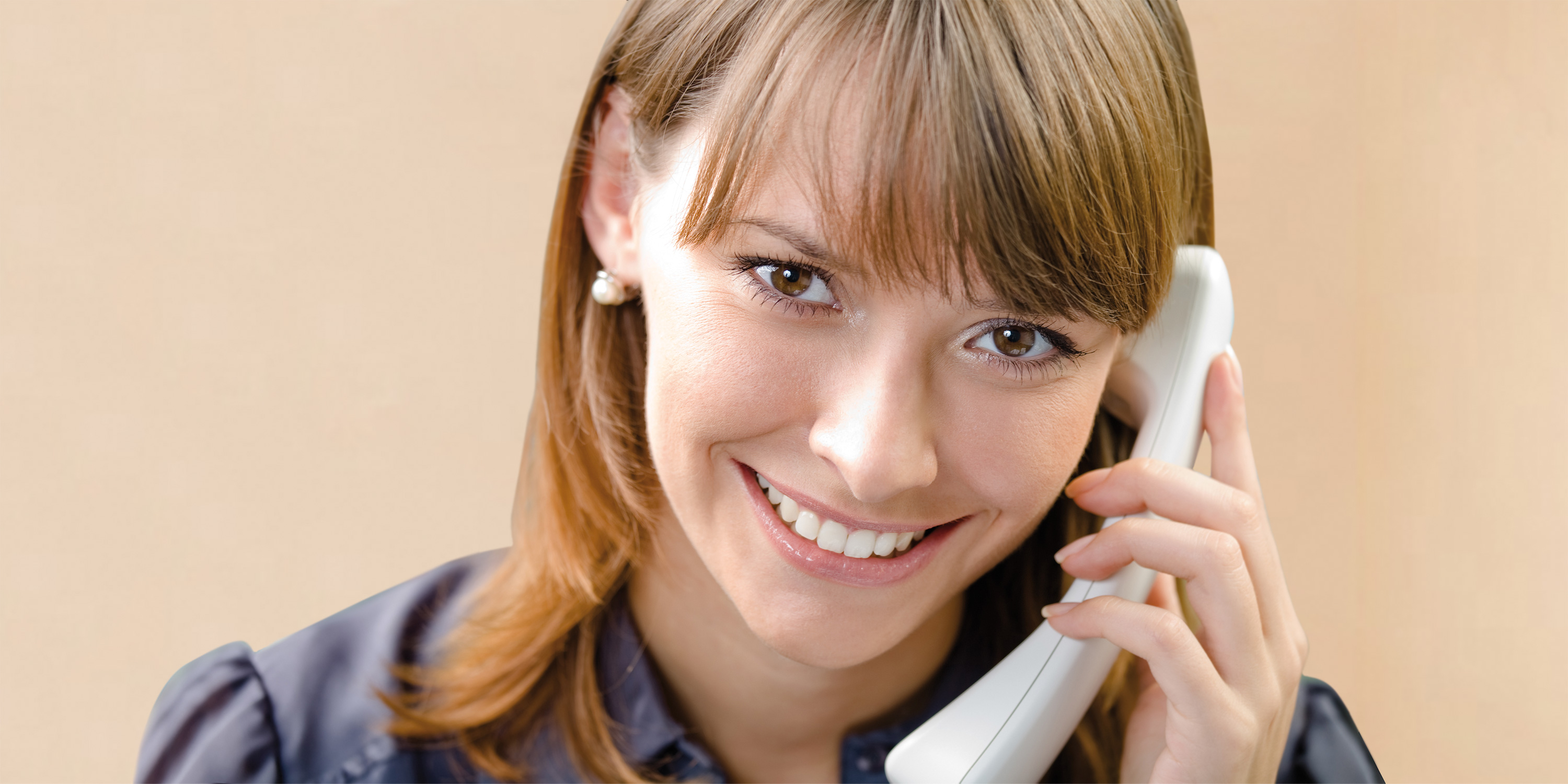 Lächelnde Frau mit Telefonhörer am Ohr