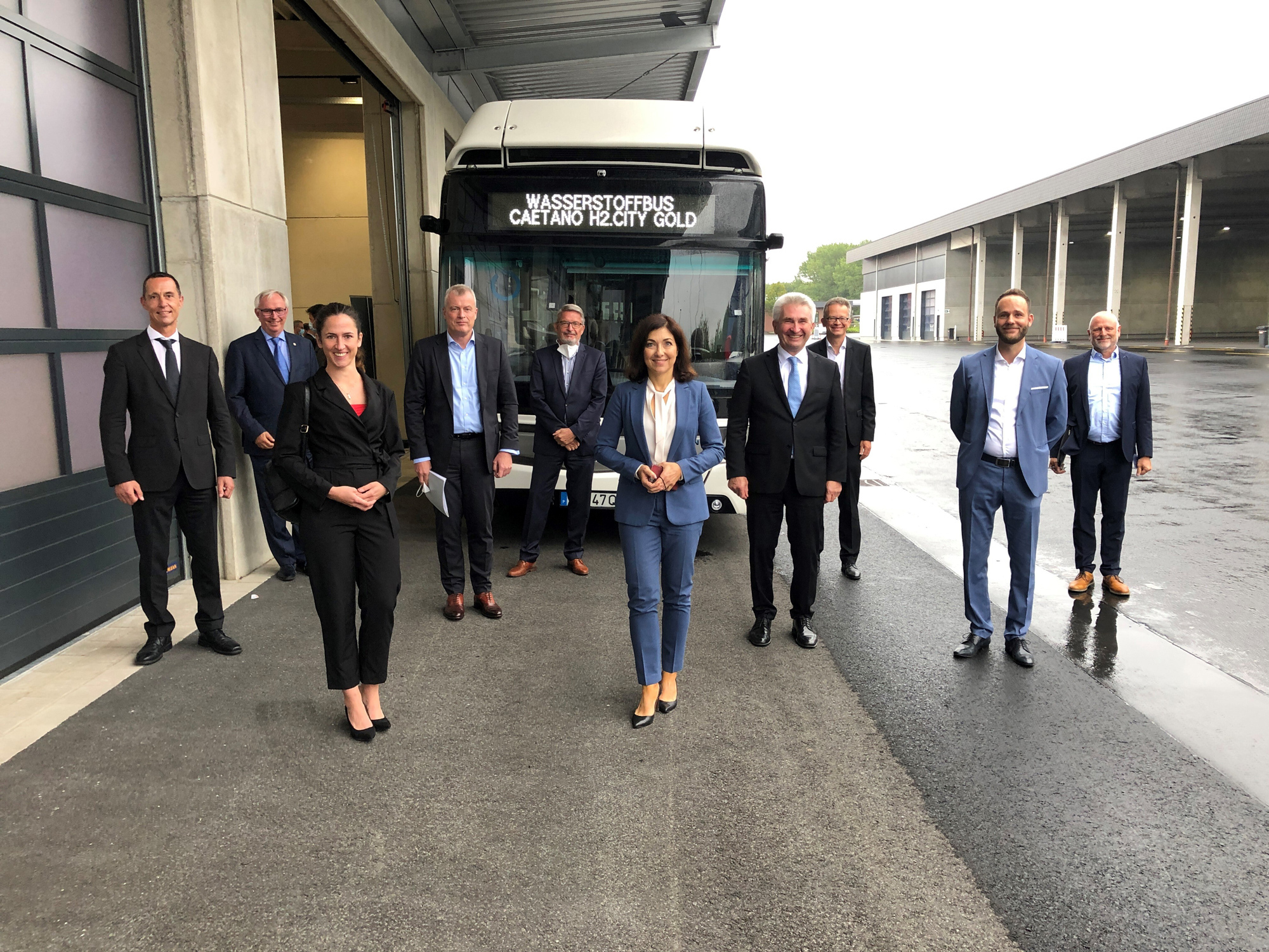 Auf dem REVG Betriebshof: Vor einem Wasserstoffbus stehen mehrere Menschen, darunter die Geschäftsführung der REVG, der Verkehrsminister NRW und  der Stadt Kerpen.
